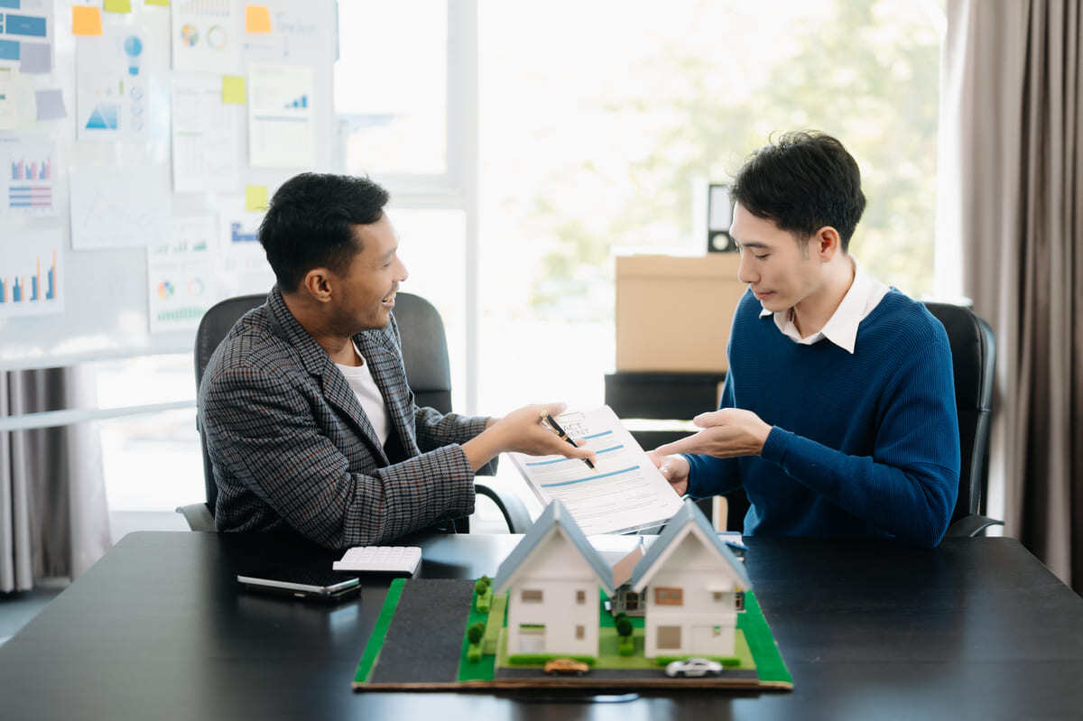 Professionals meeting next to model houses.